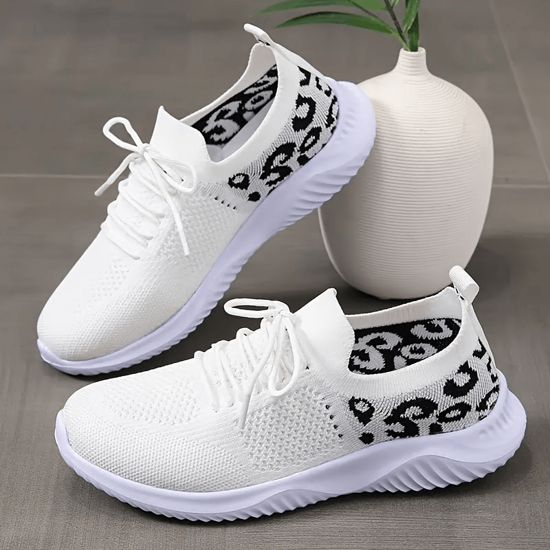 Breathable mesh leopard print sports sneakers for women with soft soles and lace-up design, placed beside a white vase.